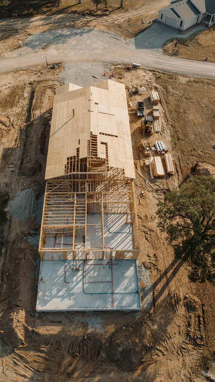 An aerial view of a ranch home blueprint under construction, showing simplified plumbing.