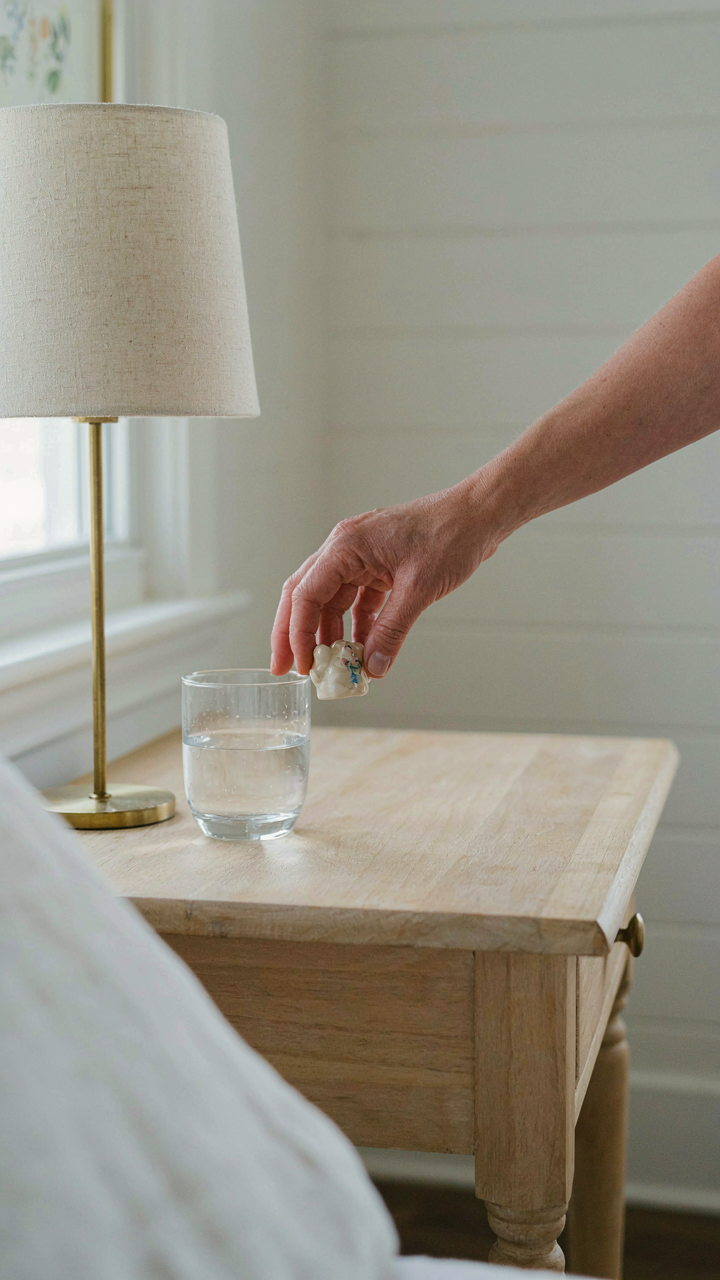 A hand removing a decorative trinket from a clean nightstand.