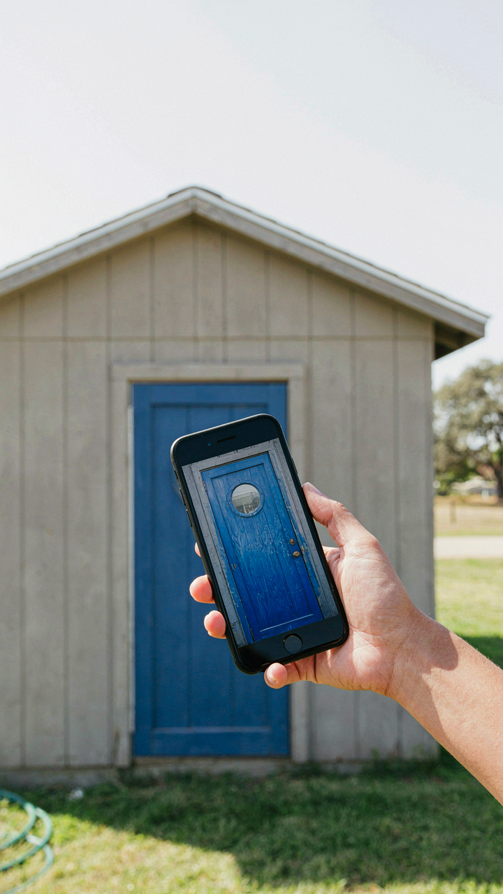 A person shows a contractor a unique blue shed door on a smartphone.