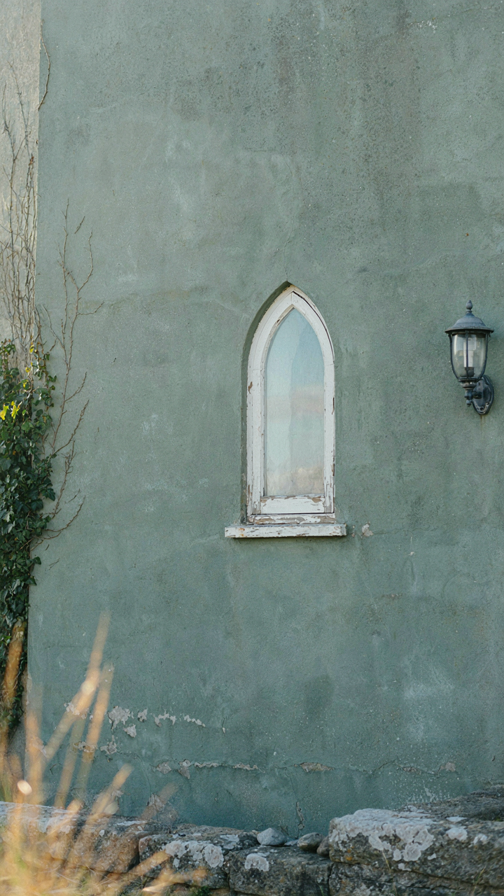 A weathered, muted sage green cottage wall with subtle fading.