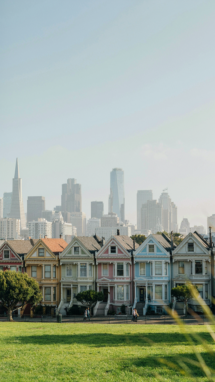 The iconic Painted Lady houses on Alamo Square, San Francisco, with the city skyline behind them.