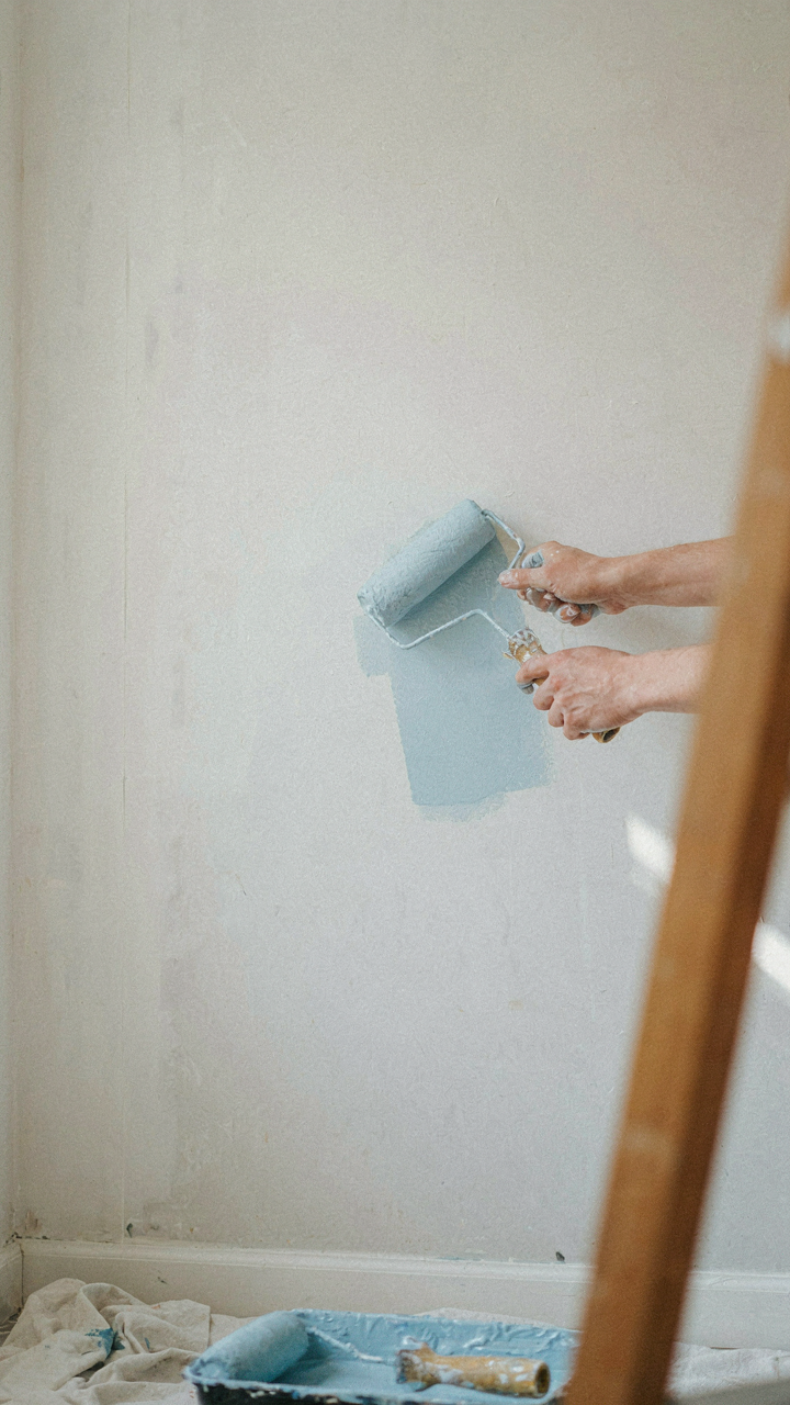 Person's hands painting a plain drywall, illustrating design choices.