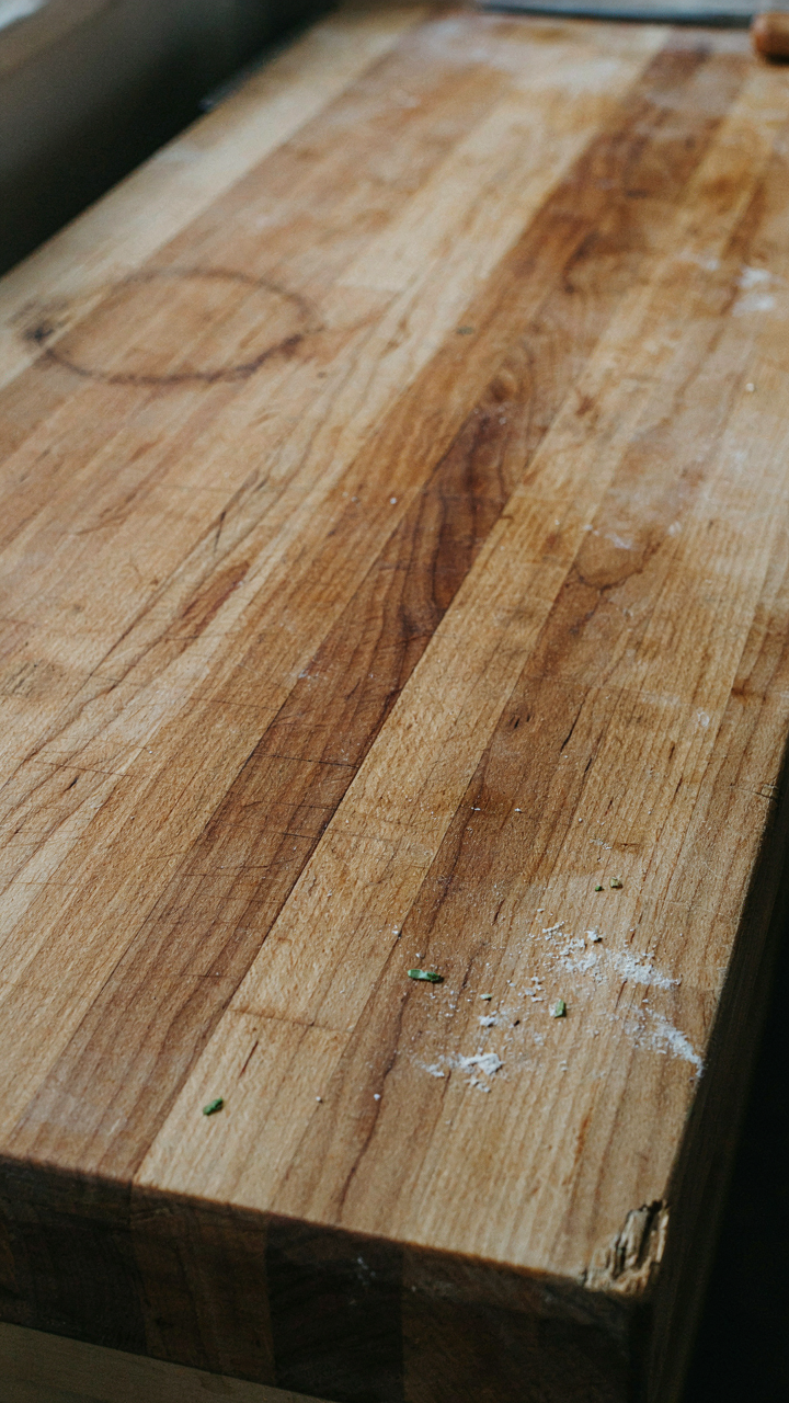 A well-worn wooden butcher block counter with many marks.