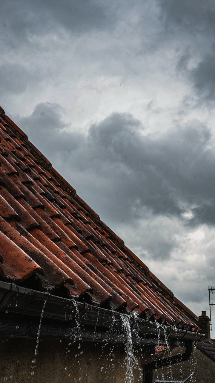A steep gable roof sheds heavy rain during a storm.