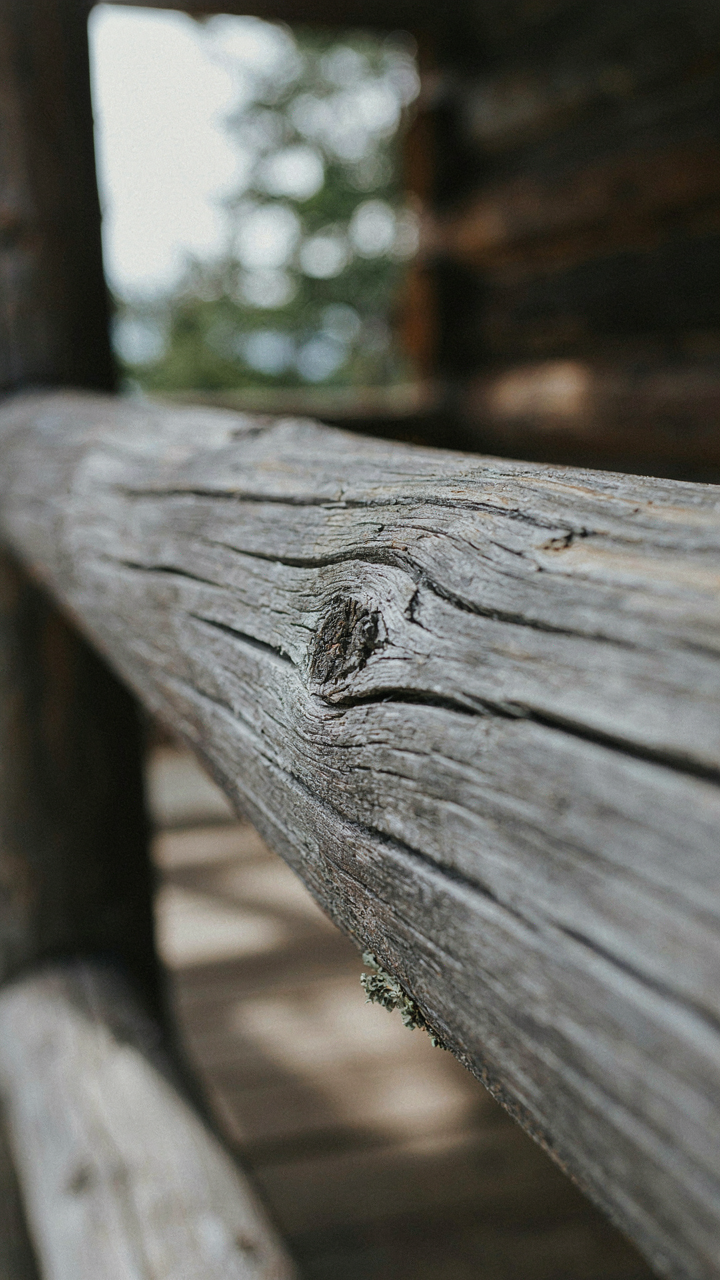 Close up of a weathered wooden beam on a cabin porch showing its natural patina.
