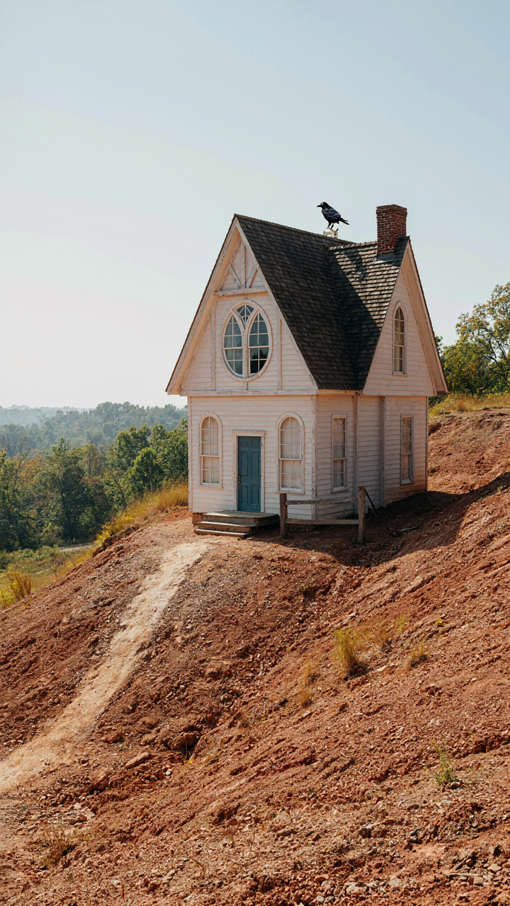 A generic storybook cottage built awkwardly on a sloped, unsuitable plot of land.