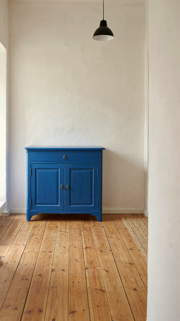 A hand-painted blue cabinet in a sparse, decluttered swedish cottage room.