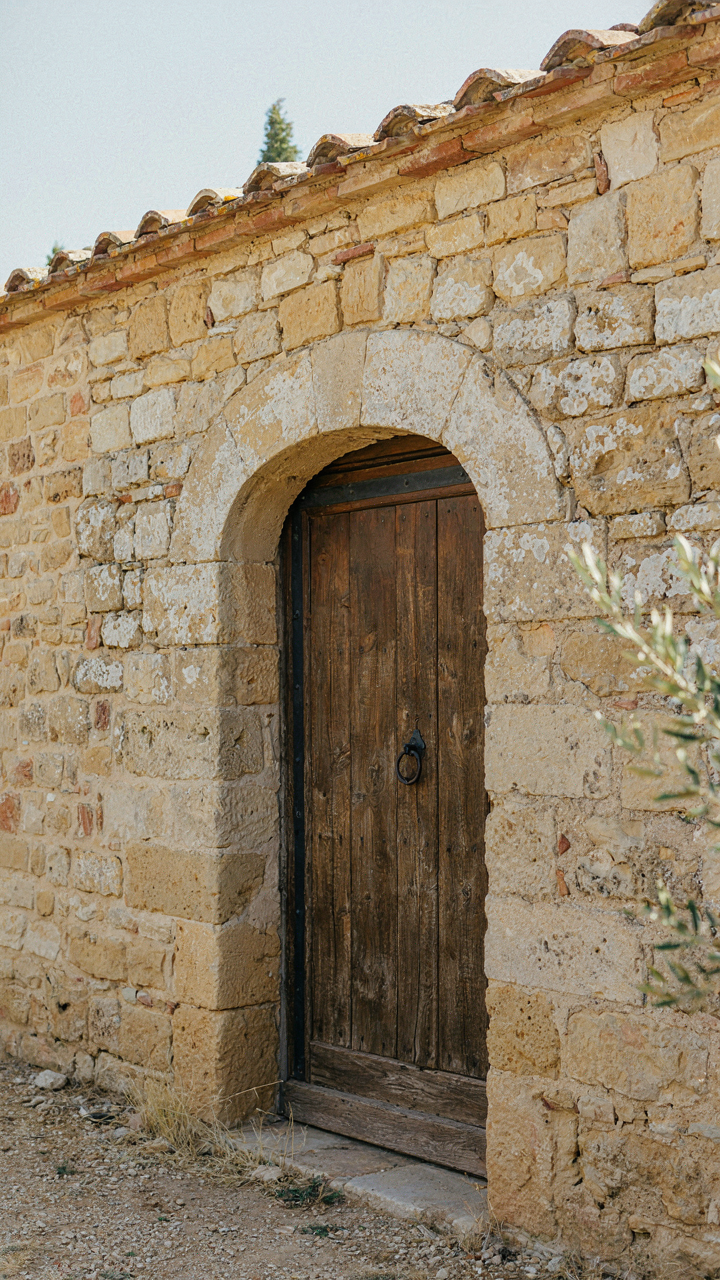 A sturdy wooden barn door set in thick stone walls of an old farmhouse.