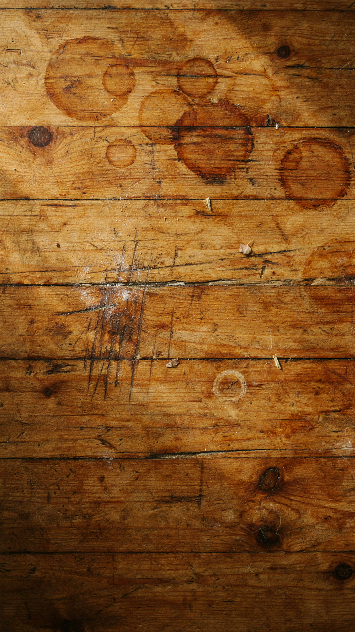 A close-up of a well-worn, reclaimed wood farmhouse dining table surface.