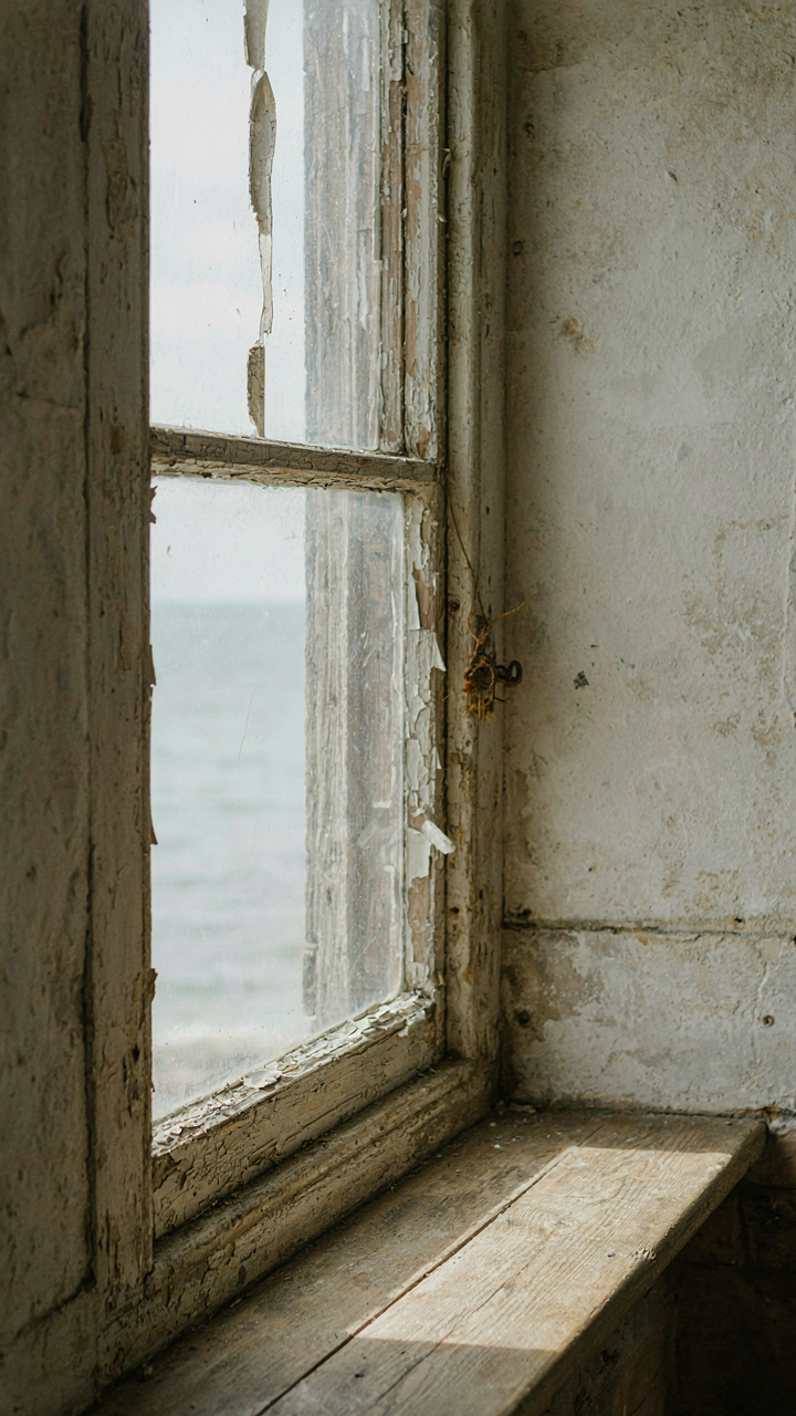 A close-up of a weathered window frame in a coastal cottage.