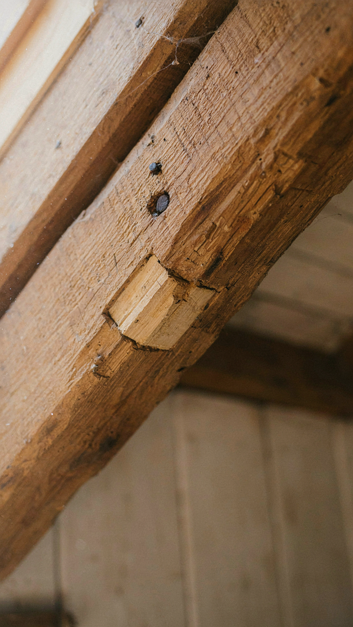 A close-up of an exposed, rough wooden beam in a barn loft bedroom.