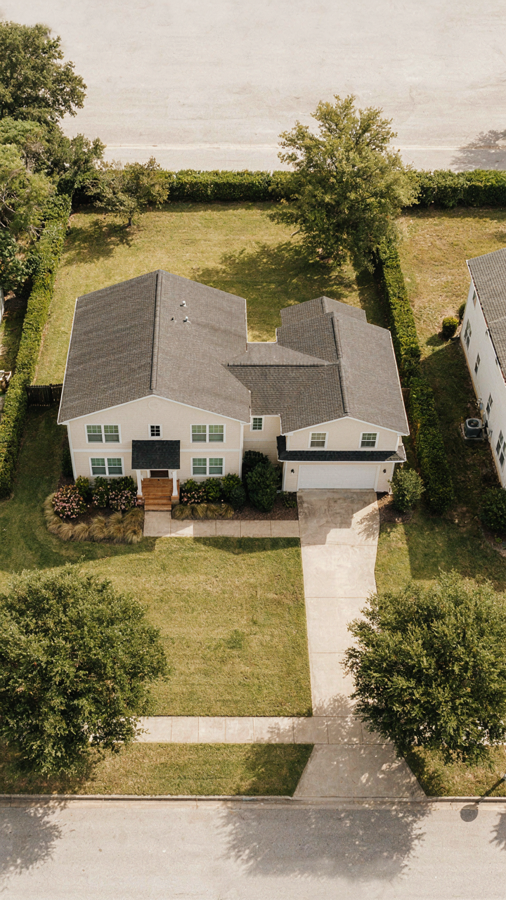An aerial view of a small cottage house with garage nested neatly.