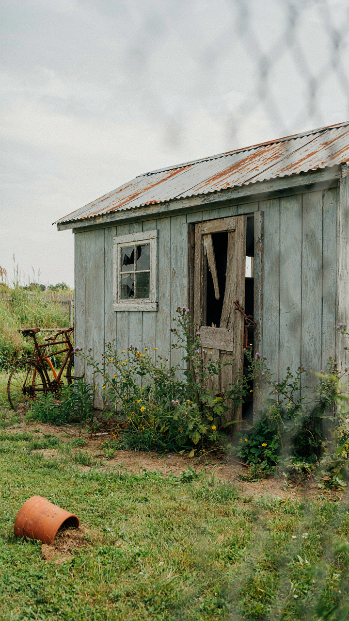 An old, neglected garden shed with a broken door, representing functional failure.