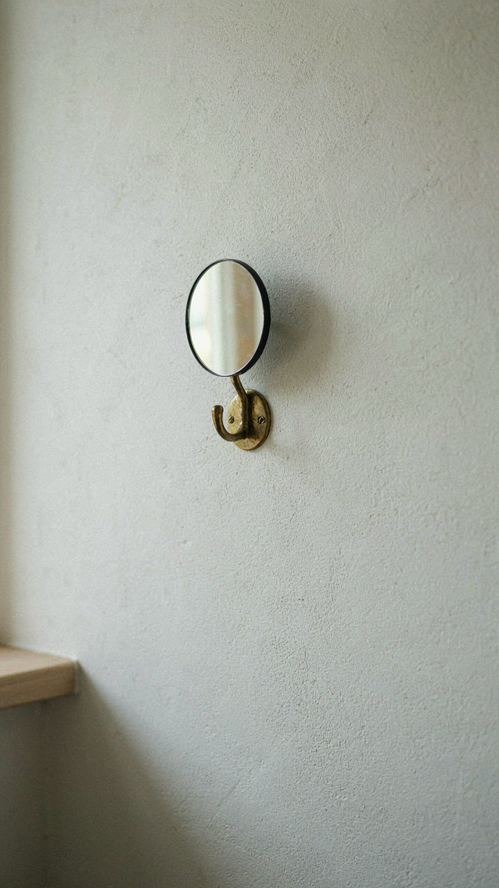 A clear wall in a cottage mudroom with a single hook for keys and a mirror.