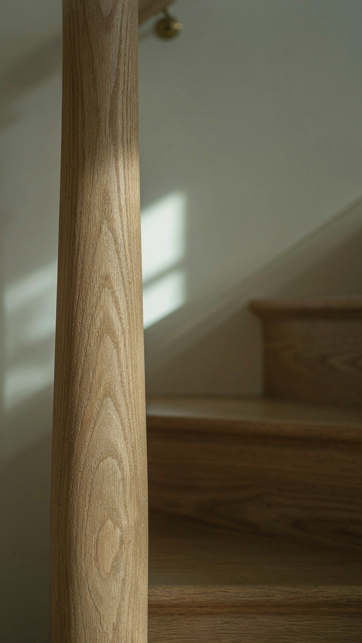 Close up of quarter-sawn wood grain on a polished newel post, showing fine lines.