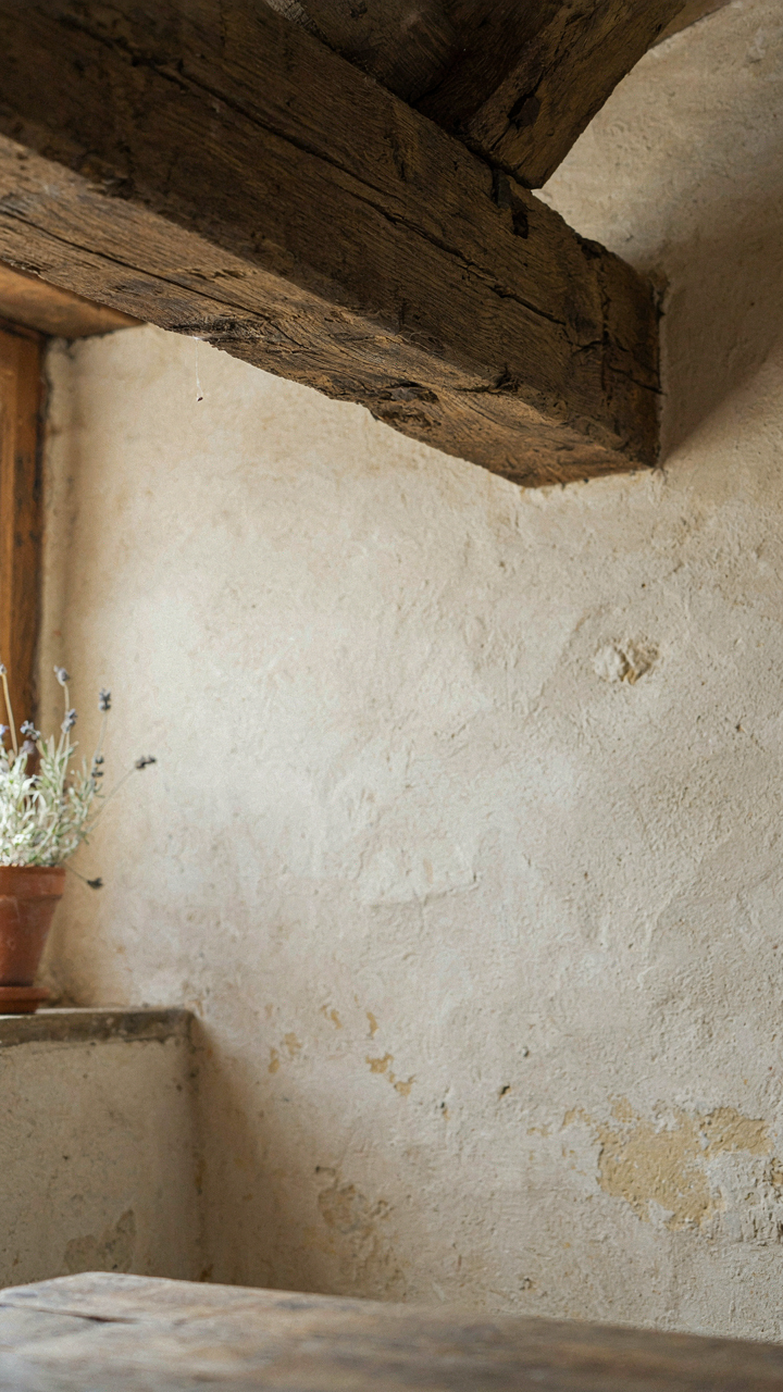 An ancient, exposed wooden beam supports the ceiling of a French country cottage.