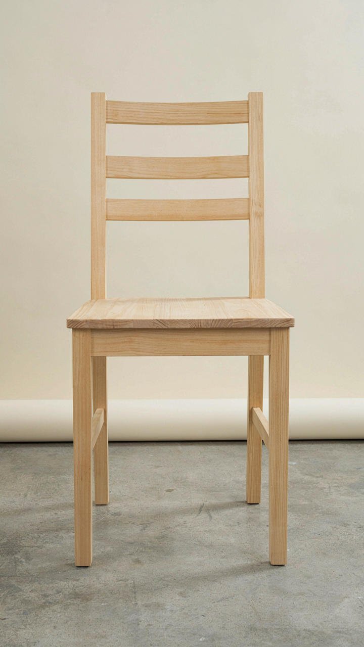 A close-up of a sturdy, well-crafted pale birch wooden chair.