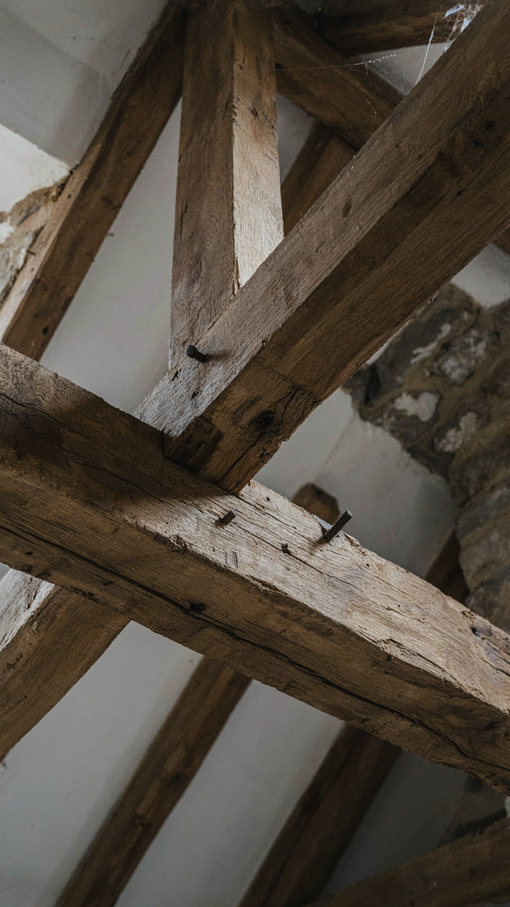 Large, exposed timber cottage ceiling beams in an ancient stone building.