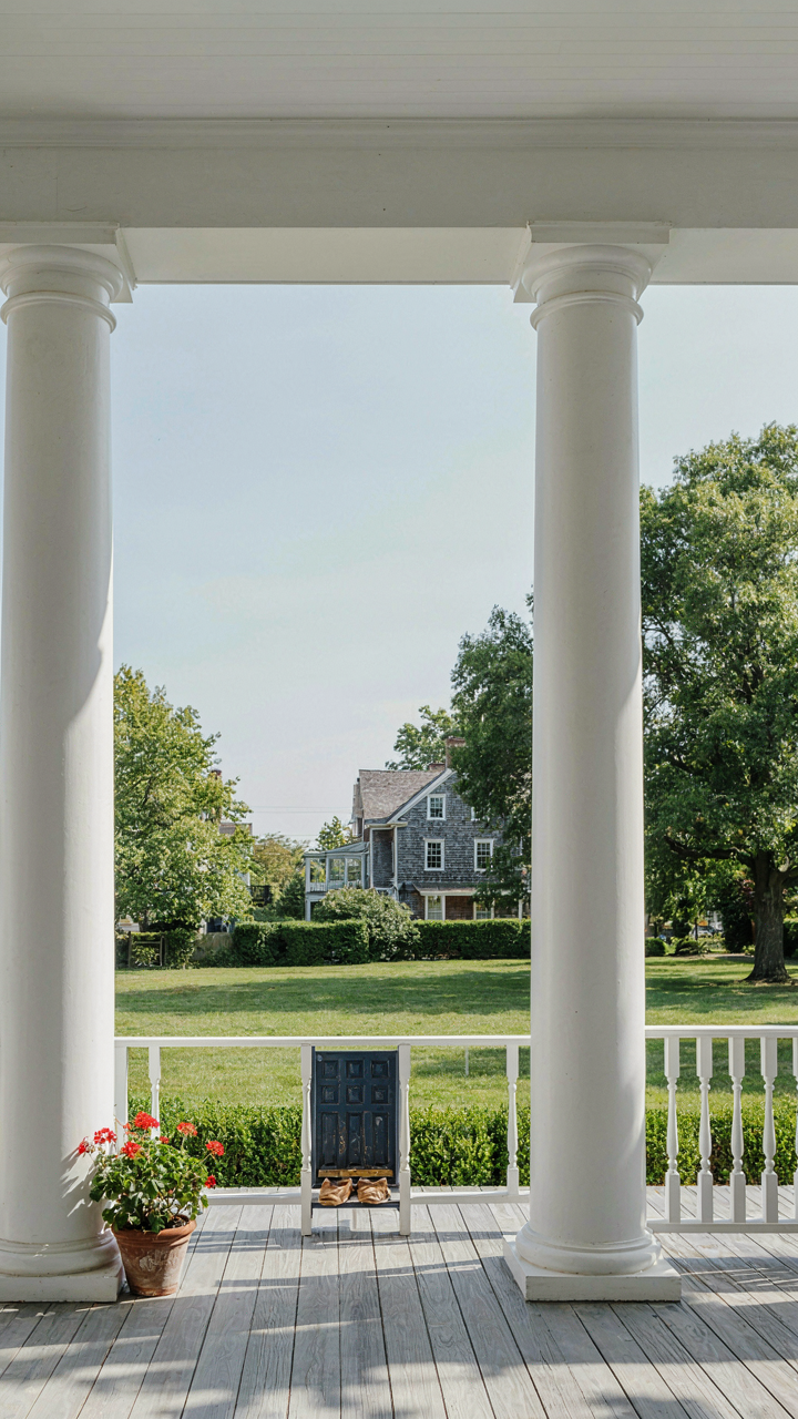 A simple colonial revival porch with thick columns and a modest balustrade.