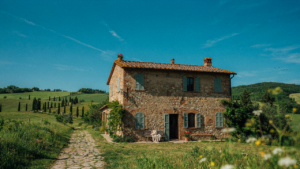 A beautiful Tuscan farmhouse with warm stone walls and a red tile roof under a clear sky.