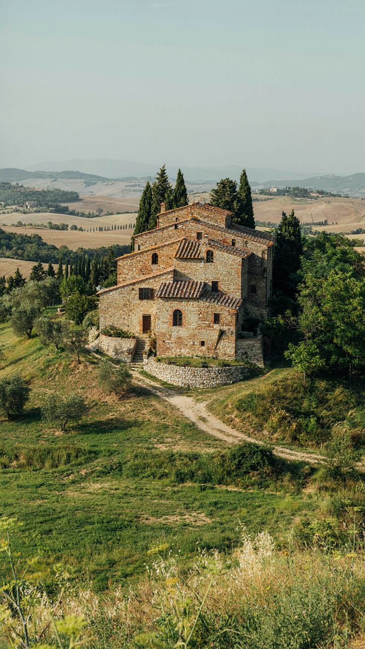 An old stone farmhouse built into a sloping hill, blending with the land.