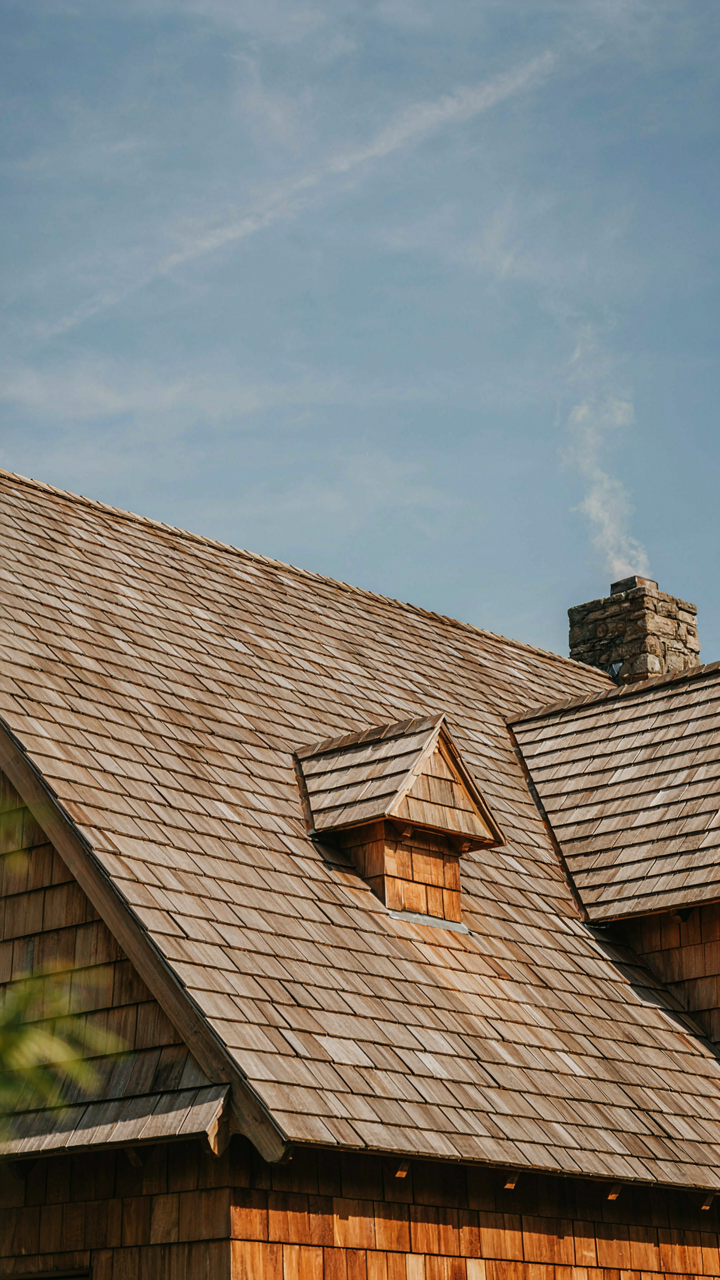 A steep-pitched cottage roof with deep eaves, made of natural wood shingles.