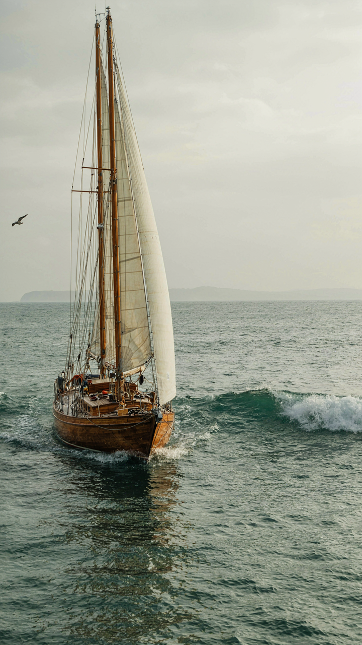 A traditional wooden sailboat weathers a calm storm, its design distributing stress.