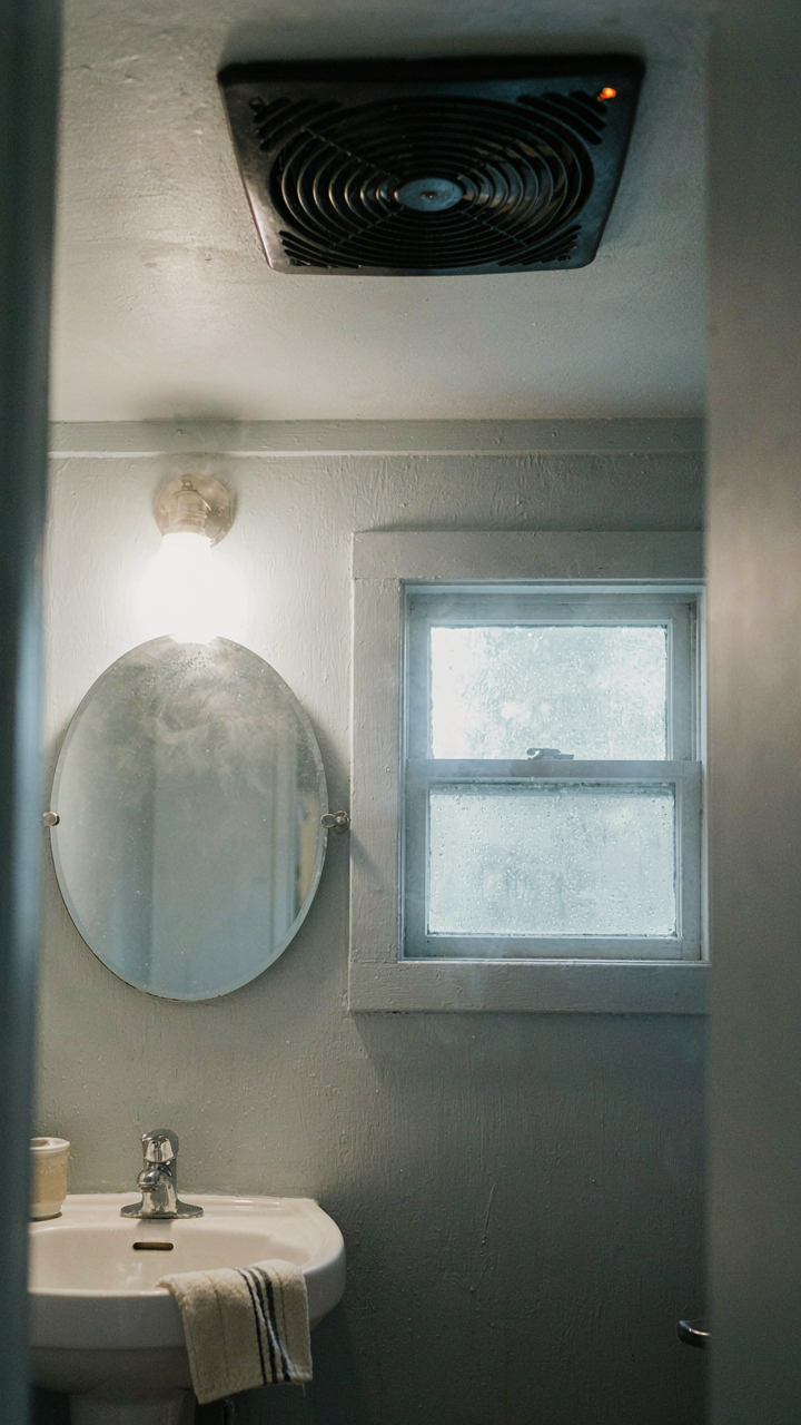 A powerful exhaust fan grille clearing steam in a small bathroom.