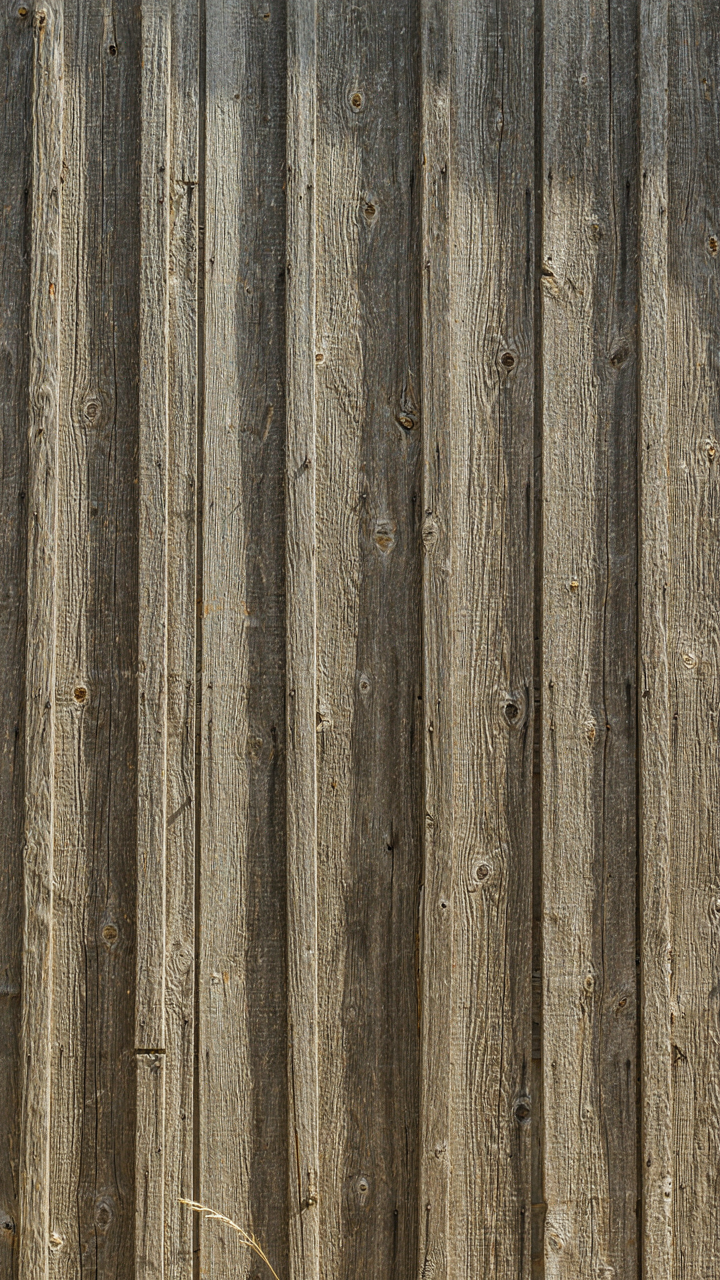 Weathered wood siding on an old barn shows natural darkening and splits.