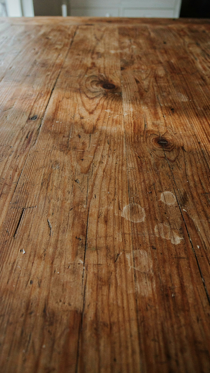 Close-up of a richly textured, old wooden dining table with visible grain.