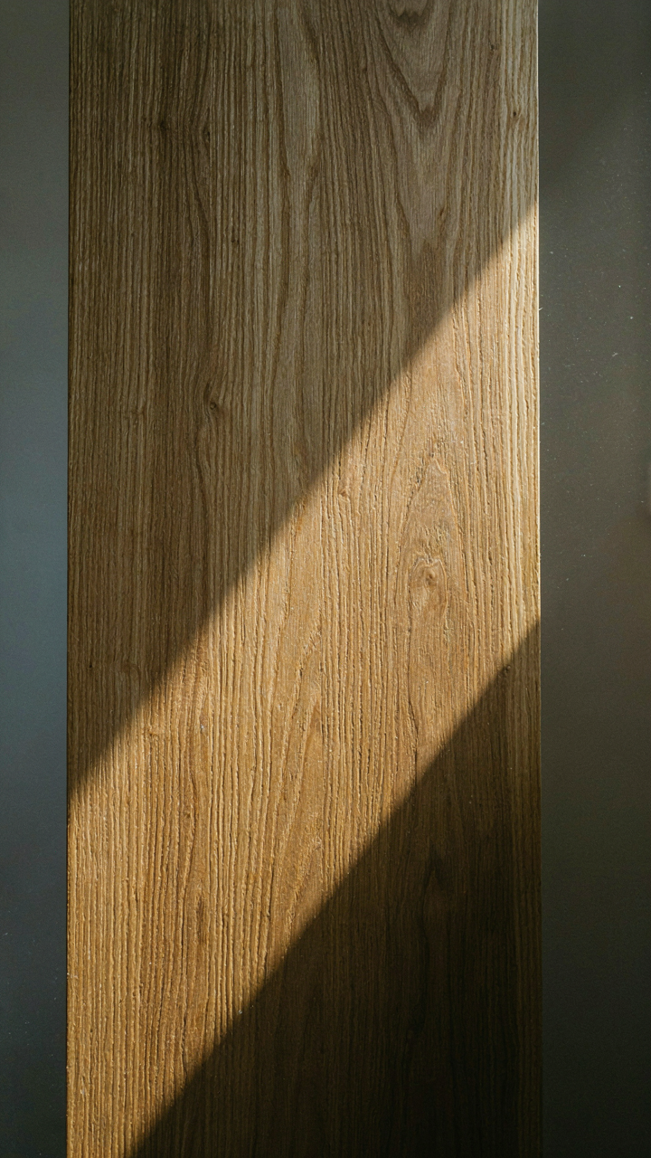 Close-up of warm quarter-sawn oak wood grain, lit by a sunbeam.