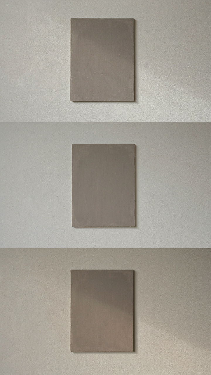 A warm gray paint swatch on a wall, showing subtle color changes.