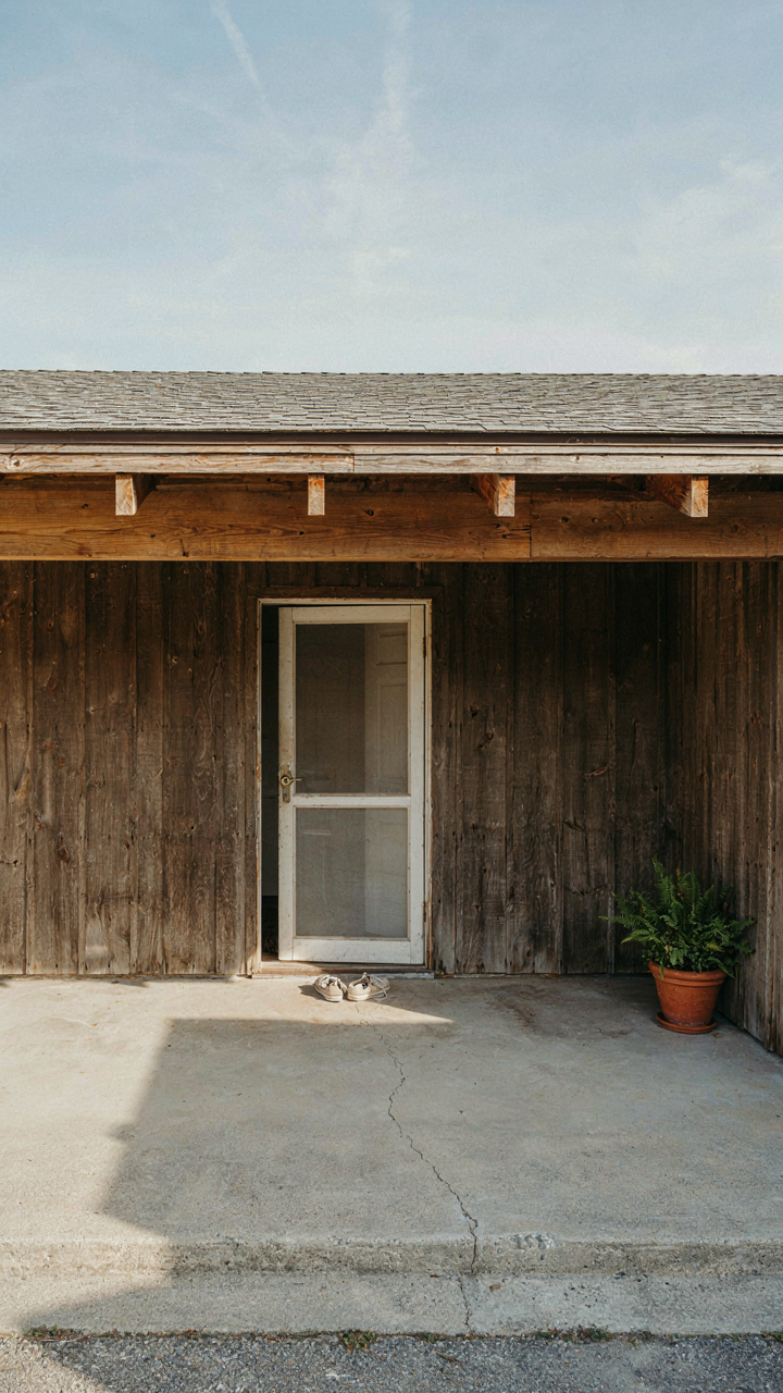 A deep roof overhang shades a concrete tiny cabin porch floor.