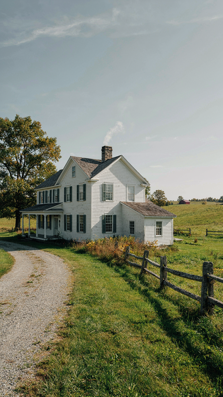 A majestic 19th-century white farmhouse with asymmetrical roof lines.