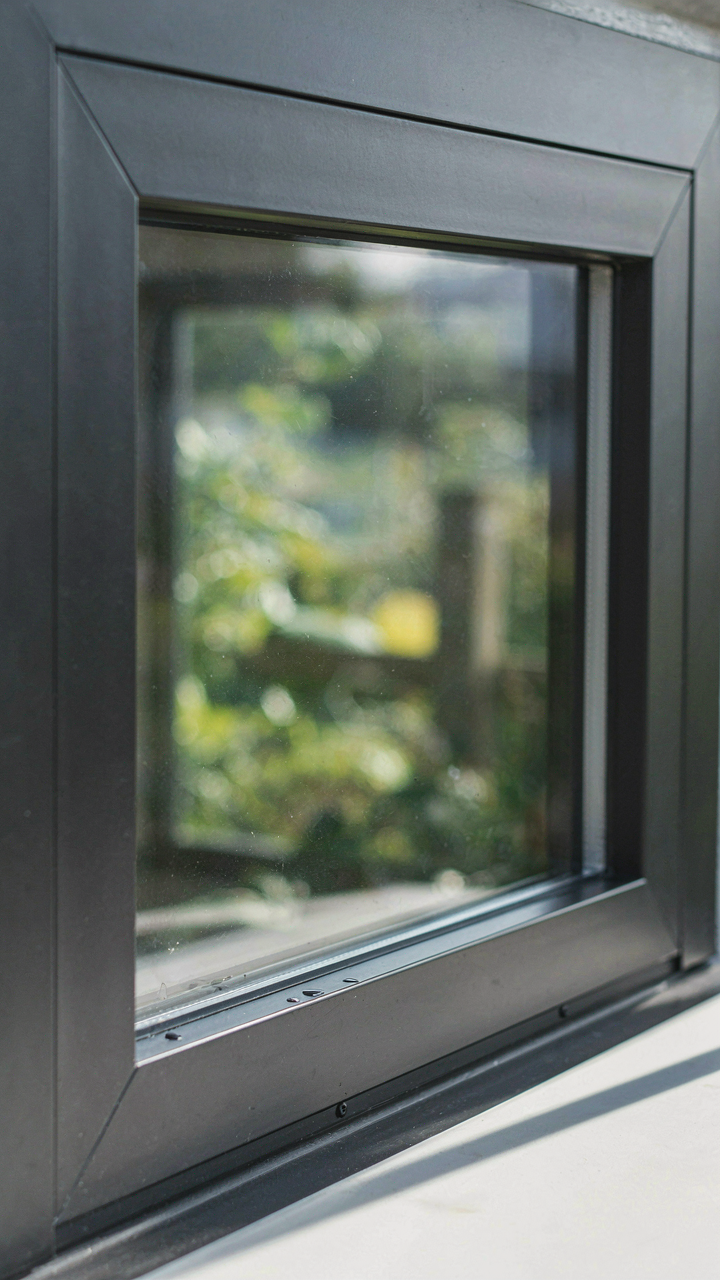 A close up of a well-sealed modern garden shed window frame with clear drainage.