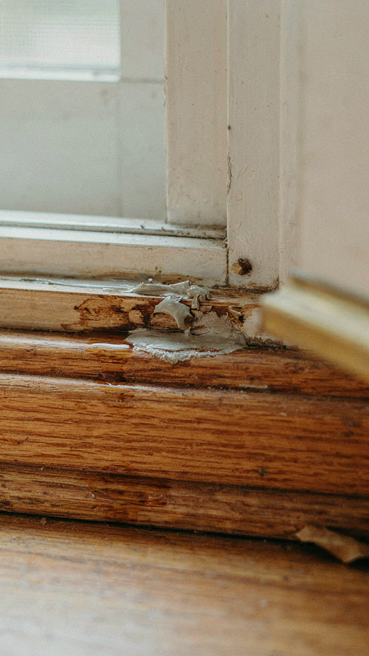 Cracked caulk on a wooden front door threshold, signaling a need for repair.