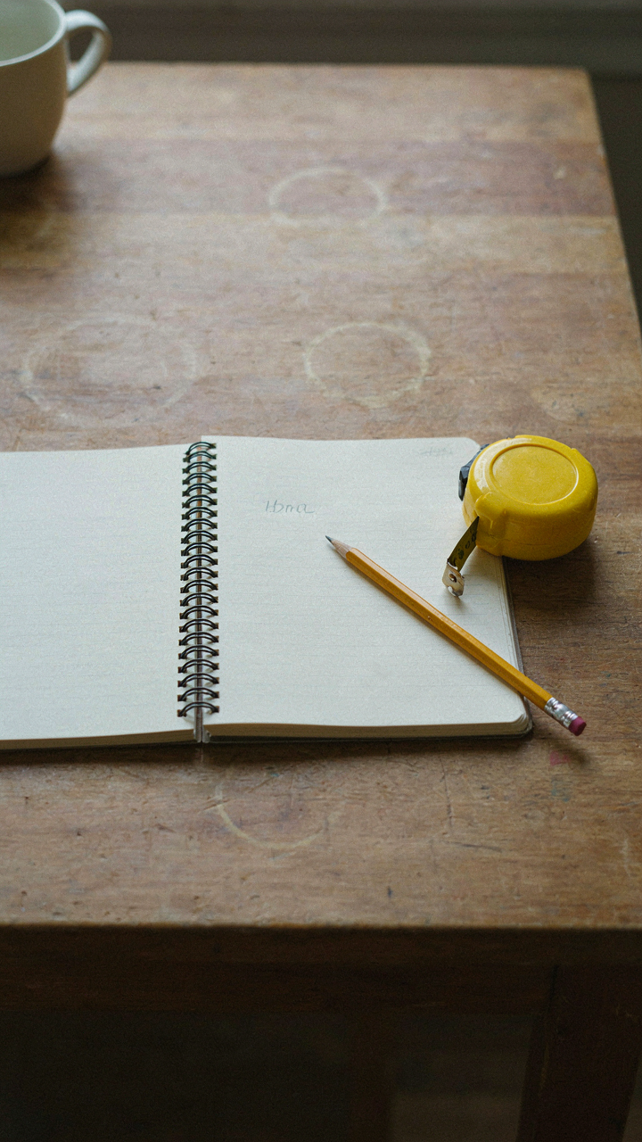 A notebook open to a single goal, next to a measuring tape.