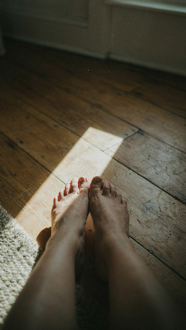 Bare feet on worn wooden floorboards in a sunny country home.