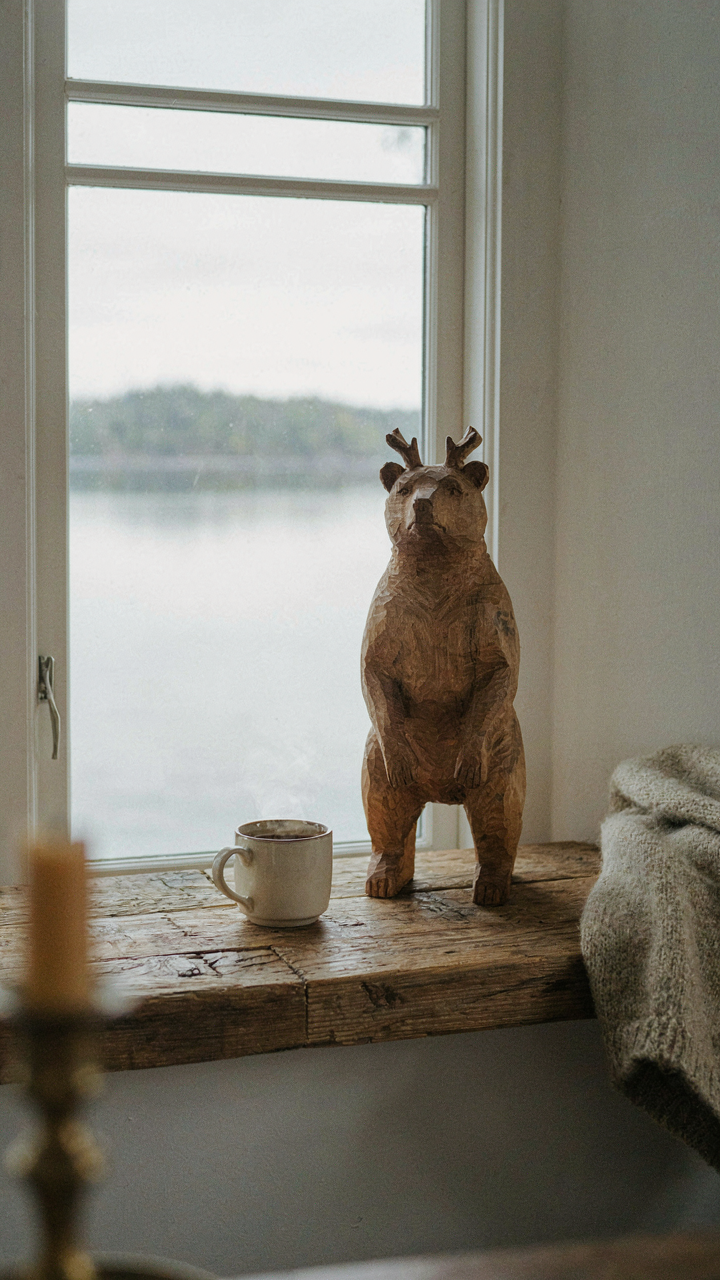A single wooden carving sits on a rustic mantelpiece in a lake house.